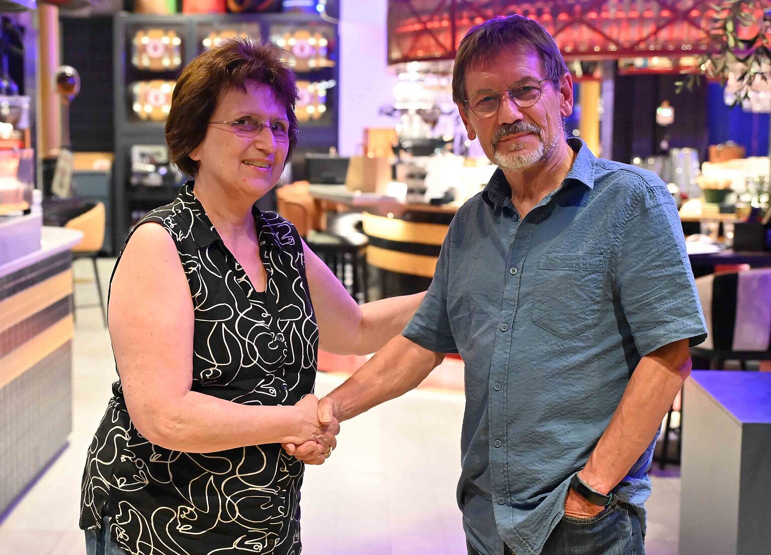 Ein Mann gratuliert einer Frau mit Handschlag zur Wahl – Frank Bugge gratuliert seiner Nachfolgerin Barbara Czernek zur Wahl.