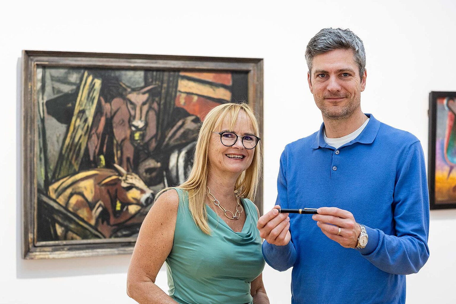 DJV Hessen „Feder für die Pressefreiheit“ 2025 Initiatorin Dr. Gabriela Blumschein-Grossmayer mit Schirmherr Ingo Zamperoni vor dem Gemälde "Ochsenstall (Vieh im Pferch)" von Max Beckmann (1884 - 1950). – DJV Hessen widmet „Feder für die Pressefreiheit“ Rukhshona Khakimova. Initiatorin Dr. Gabriela Blumschein-Grossmayer mit Schirmherr Ingo Zamperoni, in seiner Hand hält er die Feder. Im Hintergrund "Ochsenstall (Vieh im Pferch)" von Max Beckmann (1884 - 1950) im Museum Weisbaden - Hessisches Landesmuseum für Kunst und Kultur.